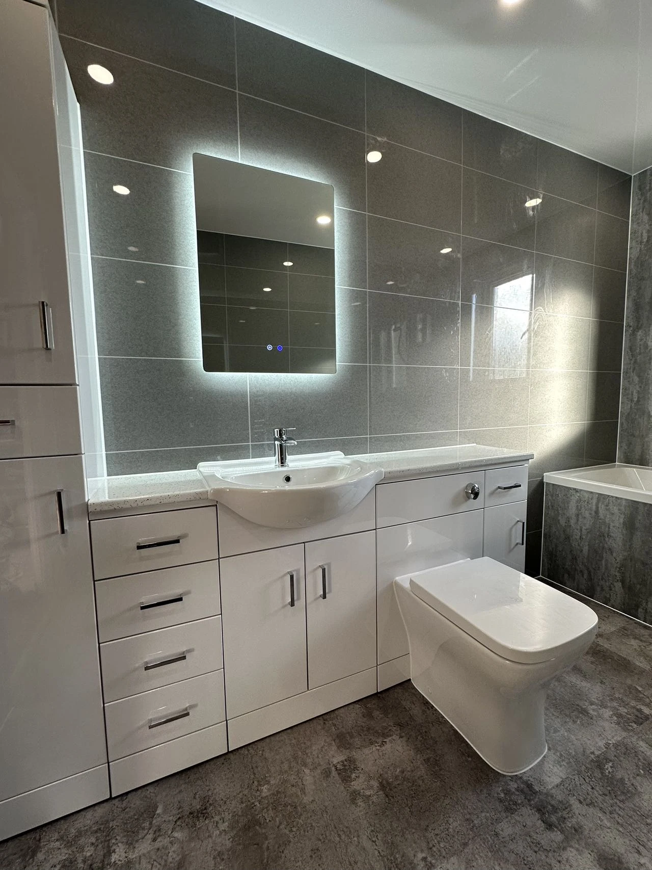 Considered bathroom detail with illuminated mirror, vanity and warm grey walls